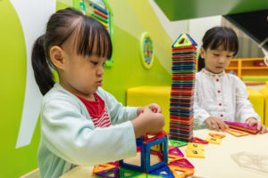 Asian Chinese little girls playing colorful magnet plastic blocks kit at indoor playground