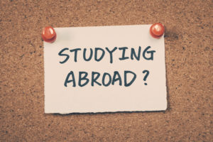 the words studying abroad written on a white piece of paper pinned to a cork board