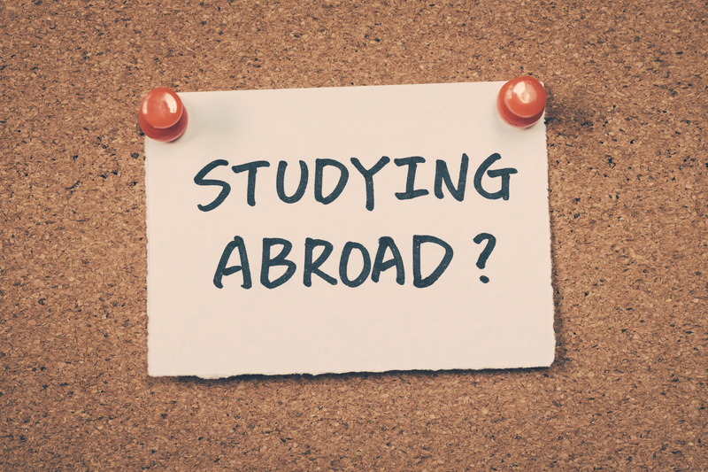 the words studying abroad written on a white piece of paper pinned to a cork board