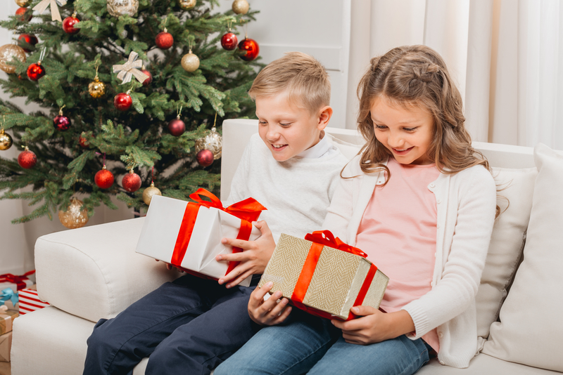 smiling kids with christmas gifts sitting on sofa