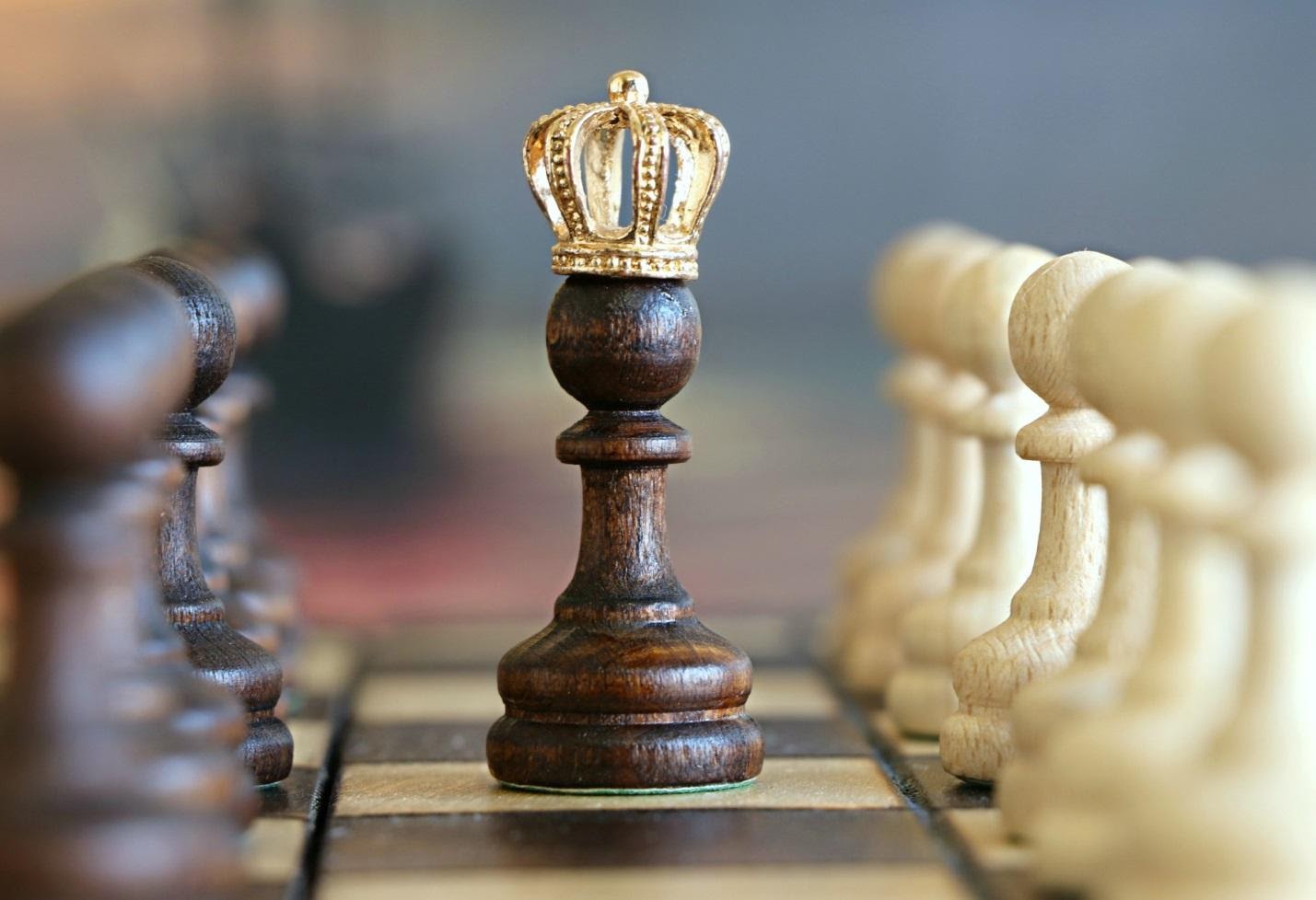 wooden chess piece with a crown on chess board