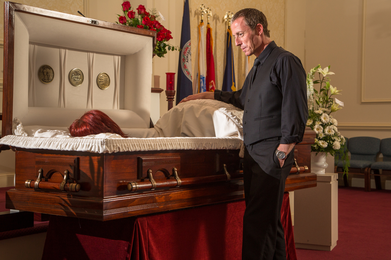 Family member standing over casket of deceased relative