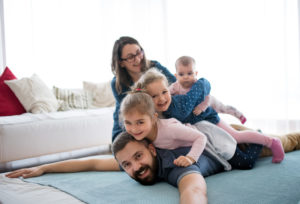 A portrait of young family with small children lying on top of each other on apartment floor