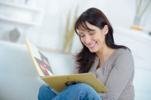 woman holding photo book sitting while smiling