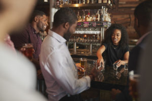 Barmaid Serving Shots To Group Of Male Friends On Night Out In Bar