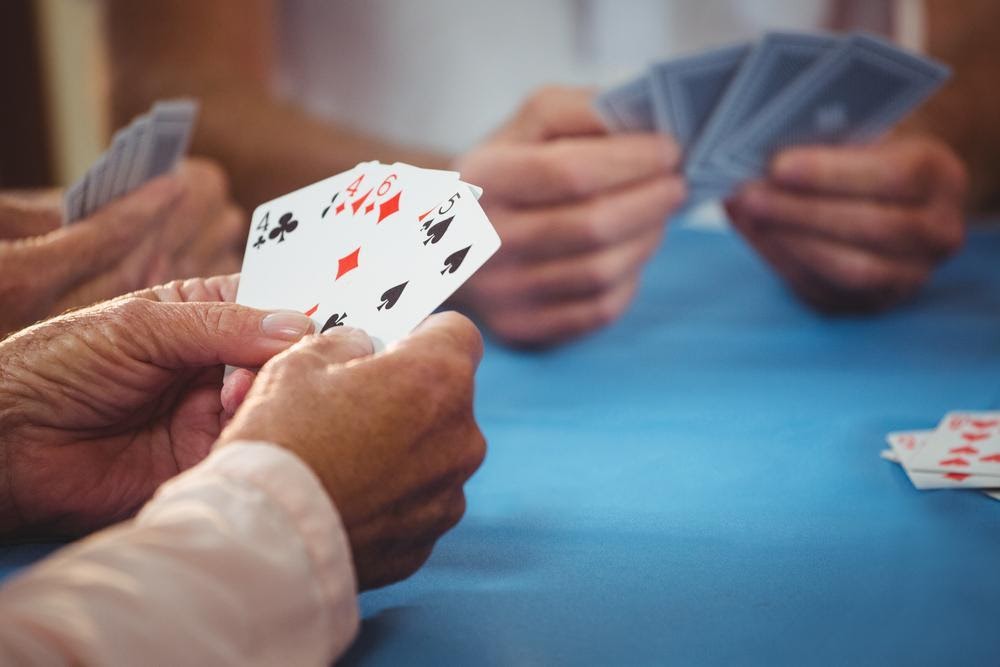 men's hands playing cards on felt table
