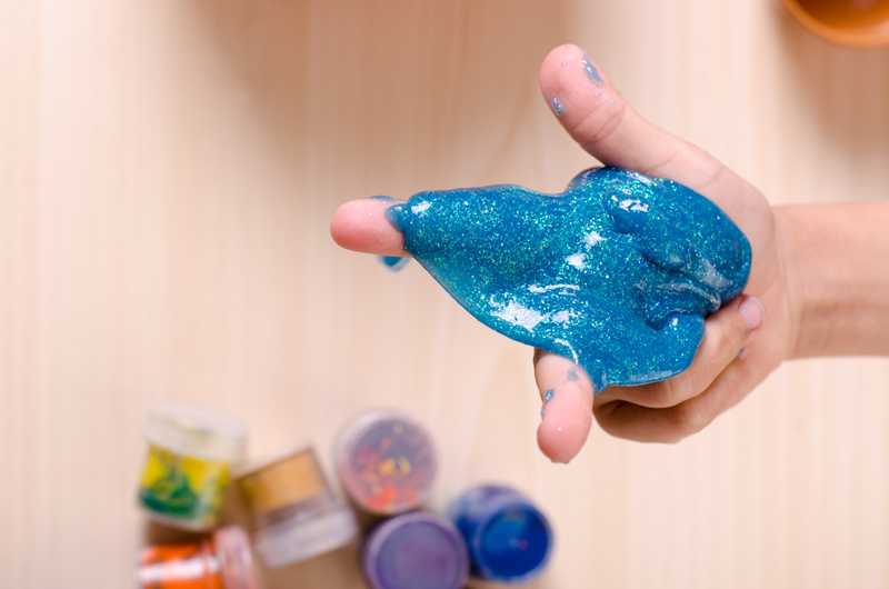 child's hand playing with blue slime