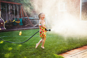 girl splashing with gardening house on backyard on summer day